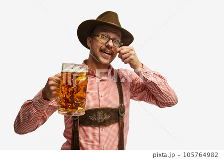 Portrait of attractive young man in hat, wearing folk Bavarian clothes, holding beer mug isolated white background. Concept of Oktoberfest Portrait of attractive young man in hat, wearing folk Bavarian clothes, holding beer mug isolated white background. Concept of Oktoberfest 105764982