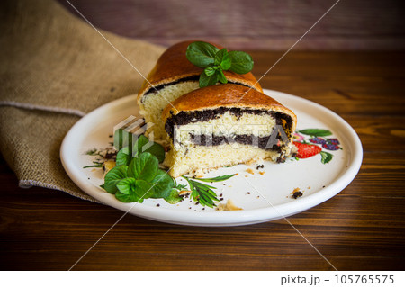 roll with poppy seeds inside on a wooden table. roll with poppy seeds inside on a wooden table. 105765575