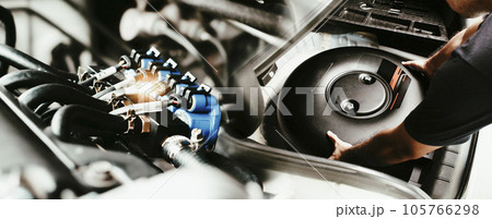 A mechanic is installing a car circle-shaped LPG or Propane tank in a spare wheel hole. 105766298
