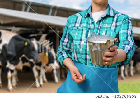 A milkmaid shows milk in a bucket. A milkmaid shows milk in a bucket. 105766808