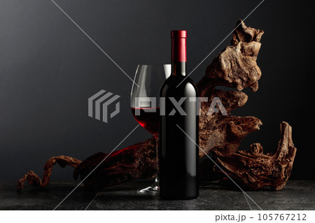 Red wine and old weathered snag on a black stone table. 105767212