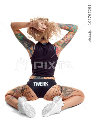 Sexy blond twerk woman with tattoed body and long curly hair is posing in studio. 105767291