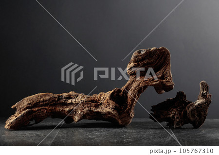 Old dry wooden snag on a black stone table. 105767310