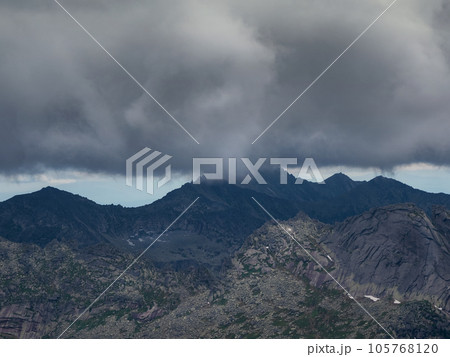 Rapid change in the weather, a thunderstorm front over high mountains, dark frightening clouds over a mountain range. 105768120