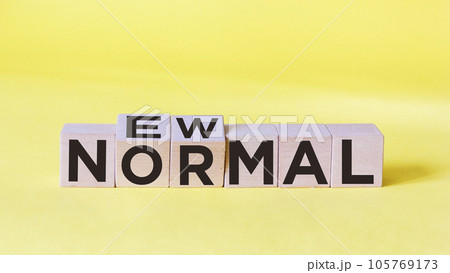 NEW PLAIN text on wooden cube and yellow background. New normal life after covid-19 pandemic 105769173
