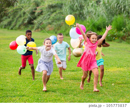 Happy tween friends with balloons chasing each...の写真素材 [105773837] - PIXTA