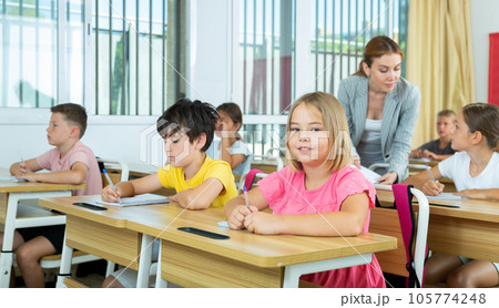 Group of school kids and teacher during lesson in classroom Group of school kids and teacher during lesson in classroom 105774248