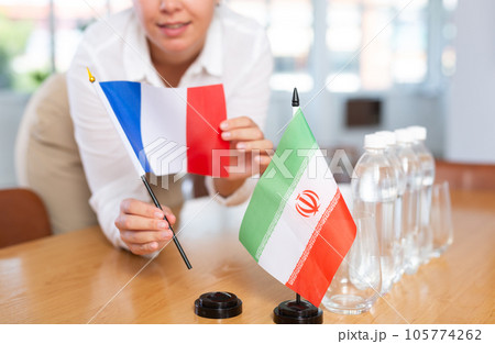 Woman secretary prepares the negotiating table - arranges flags of France and Iran 105774262