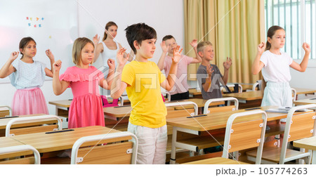 Small school kids doing physical exercises with teacher 105774263