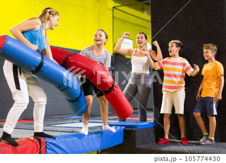 Active excited child school girls having fun and fighting with inflatable logs in amusement center Active excited child school girls having fun and fighting with inflatable logs in amusement center 105774430