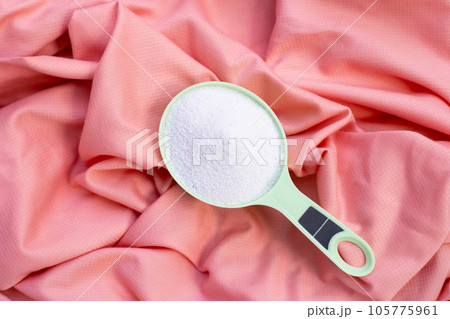 Detergent powder in measuring spoon on cloth before washing. Laundry concept. Detergent powder in measuring spoon on cloth before washing. Laundry concept. 105775961
