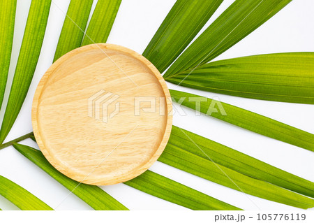 Empty wooden plate on tropical palm leaves Empty wooden plate on tropical palm leaves 105776119