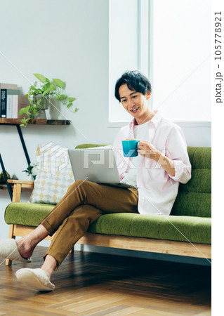 リビングでパソコンを使う若い男性 リビングでパソコンを使う若い男性 105778921