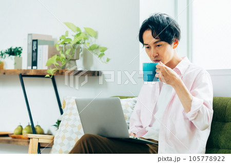 リビングでパソコンを使う若い男性 リビングでパソコンを使う若い男性 105778922