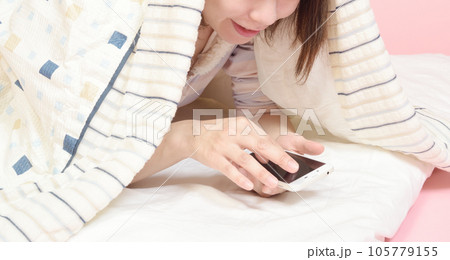 パジャマ姿でスマホを操作する女性 105779155