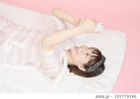 パジャマ姿でスマホを操作する女性 パジャマ姿でスマホを操作する女性 105779166