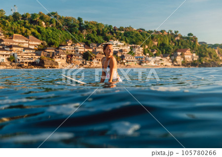 Surfer woman sitting on surfboard during surfing in ocean. 105780266