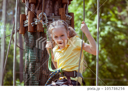 A child in a forest adventure park made of ropes. 105786256