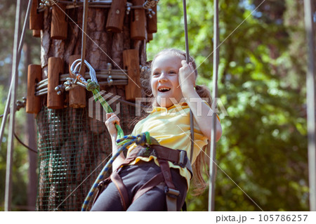 A child in a forest adventure park made of ropes. 105786257