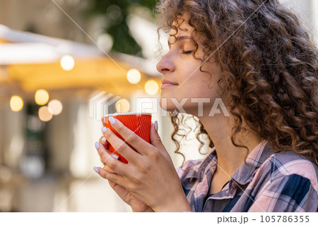 Young woman girl enjoying drinking morning coffee hot drink, relaxing, taking a break in city street 105786355