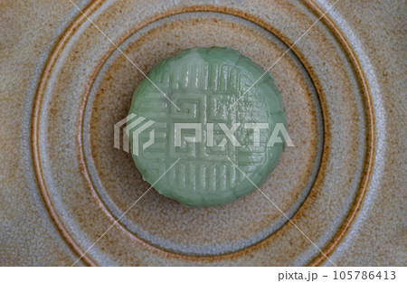 Green mooncake is filled with taro, black sesame and golden thread egg on ceramic plate. 105786413