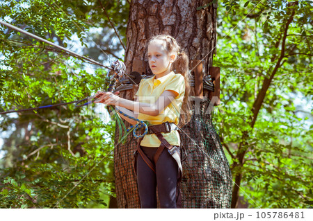 A child in a forest adventure park made of ropes. 105786481