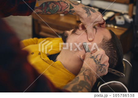 Client during beard shaving in barber shop Client during beard shaving in barber shop 105786538
