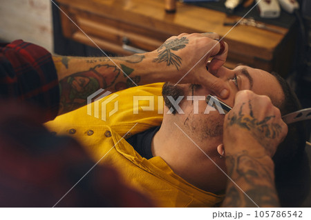 Client during beard shaving in barber shop Client during beard shaving in barber shop 105786542