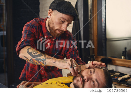 Client during beard shaving in barber shop 105786565