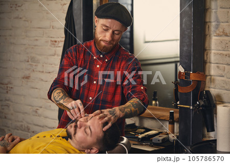 Client during beard shaving in barber shop 105786570