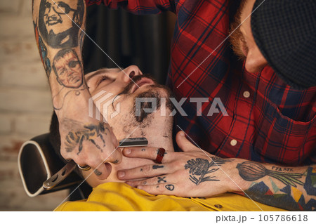 Client during beard shaving in barber shop 105786618