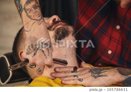 Client during beard shaving in barber shop 105786631