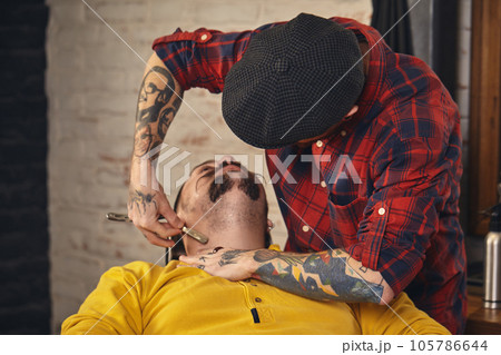Client during beard shaving in barber shop Client during beard shaving in barber shop 105786644