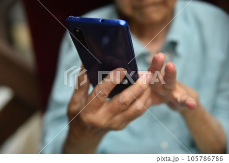 スマートフォンを操作する高齢者の手元 105786786
