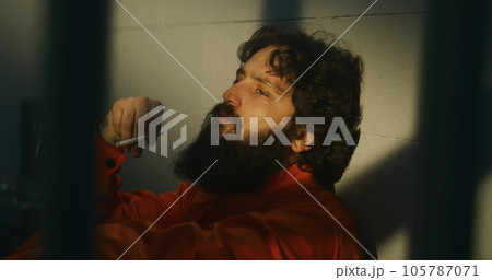 Thoughtful male prisoner lights cigarette with lighter and smokes Thoughtful male prisoner lights cigarette with lighter and smokes 105787071