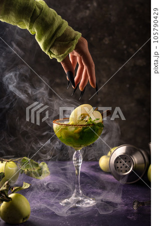 Halloween green apple cocktail with witch hand Halloween green apple cocktail with witch hand 105790429