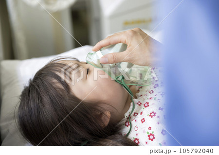 苦しそうにしている子供の患者に酸素マスクをつける看護師 105792040