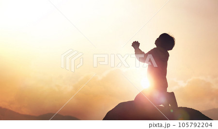 Child Christian earnestly praying to God and Jesus with both hands together under the red sunset sky and bright sunlight Child Christian earnestly praying to God and Jesus with both hands together under the red sunset sky and bright sunlight 105792204