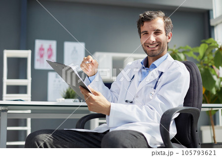 A male doctor in a white coat looks at the medical history and laughs. 105793621