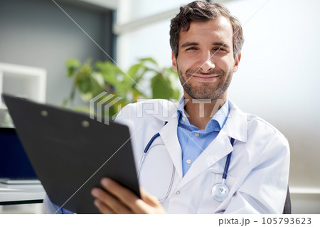 A male doctor in a white coat looks at the medical history and laughs. 105793623