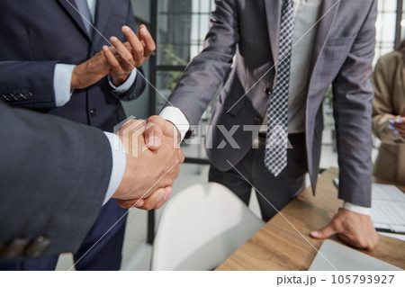 Two young businessmen are shaking hands with each other. 105793927
