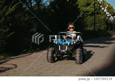 boy rides in toy mini car in park in summer 105794514