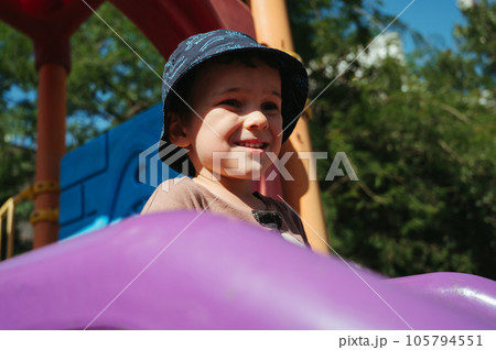 kindergarten boy plays on slide on playground in summer on the street 105794551