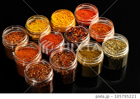 Variety of spices on a dark background in a glass bowl. Enhancement of taste. Variety of spices on a dark background in a glass bowl. Enhancement of taste. 105795221