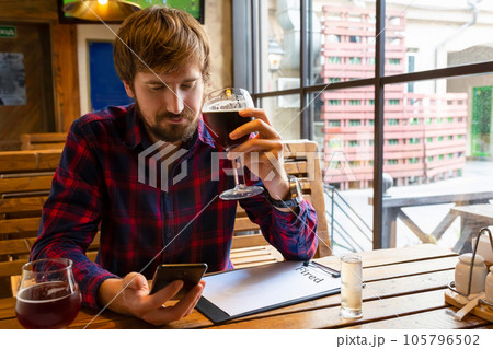 A man in a bar struggling with alcohol addiction, depression, loneliness. Drinking alcoholic. 105796502