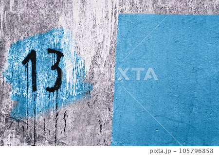 number 13 painted on dirty concrete wall on the corner of old abandoned house 105796858
