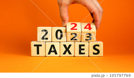 2024 taxes new year symbol. Businessman turns a wooden cube and changes words Taxes 2023 to Taxes 2024. Beautiful orange table orange background, copy space. Business 2024 taxes new year concept. 105797769