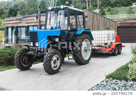 wheeled tractor with irrigation tanks on a trailer for maintenance of urban green spaces 105798170