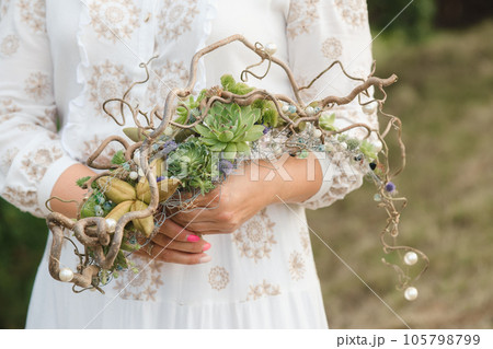 The bride holds an unusual braided wedding bouquet in her hands 105798799