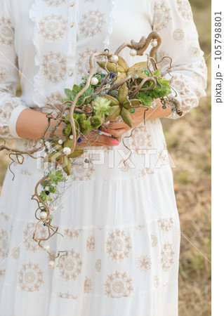 The bride holds an unusual braided wedding bouquet in her hands 105798801